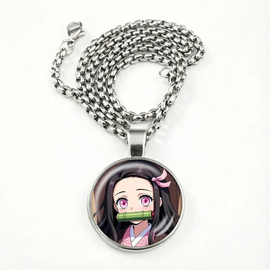 Collier cabochon montrant Nezuko en version chibi, mors de bambou vert, sous un verre bombé serti